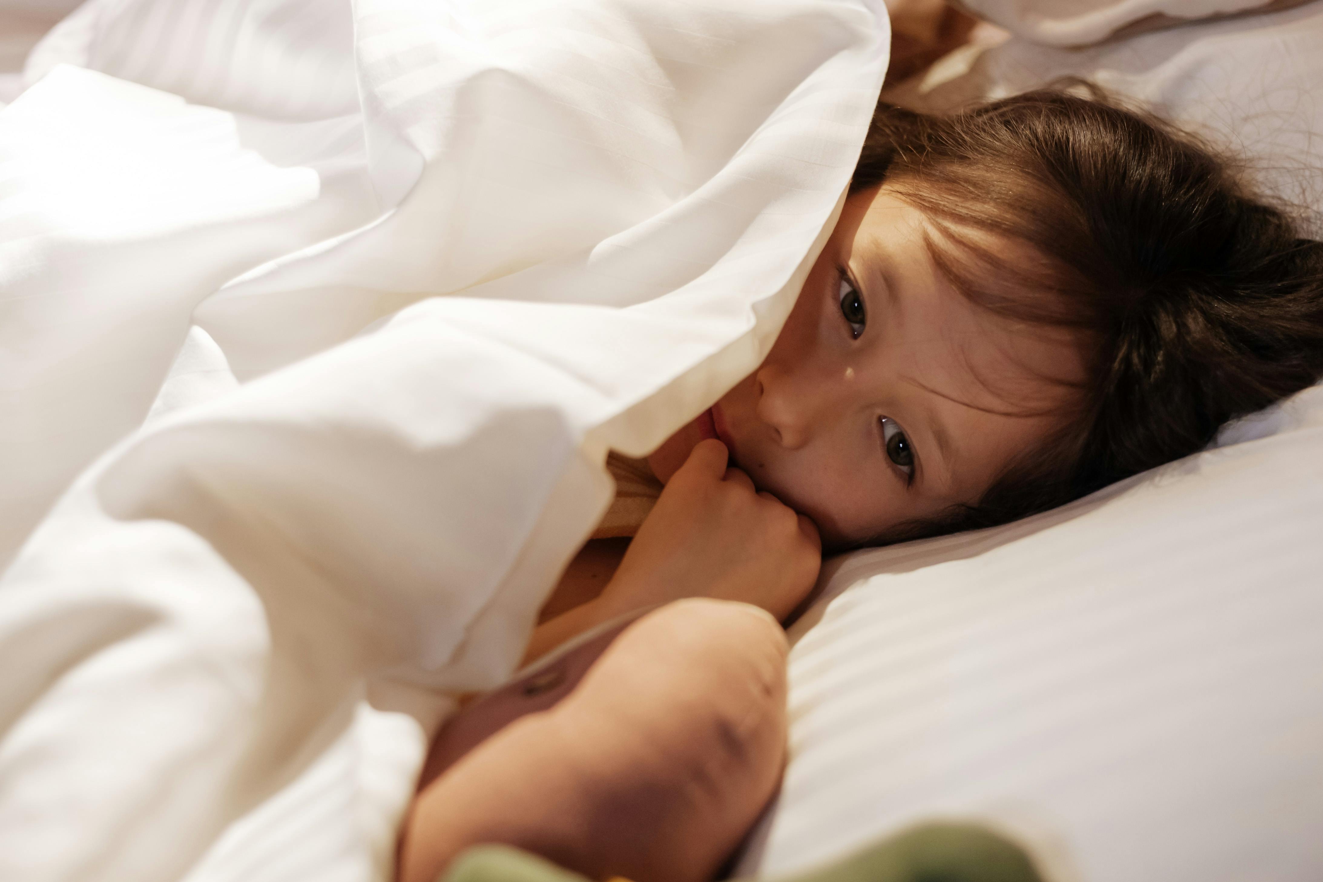 girl tucked in bed with plush toys