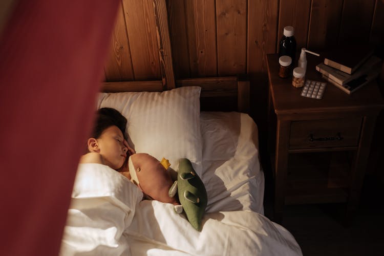 Girl Sleeping In Bed With Medicine On Nightstand