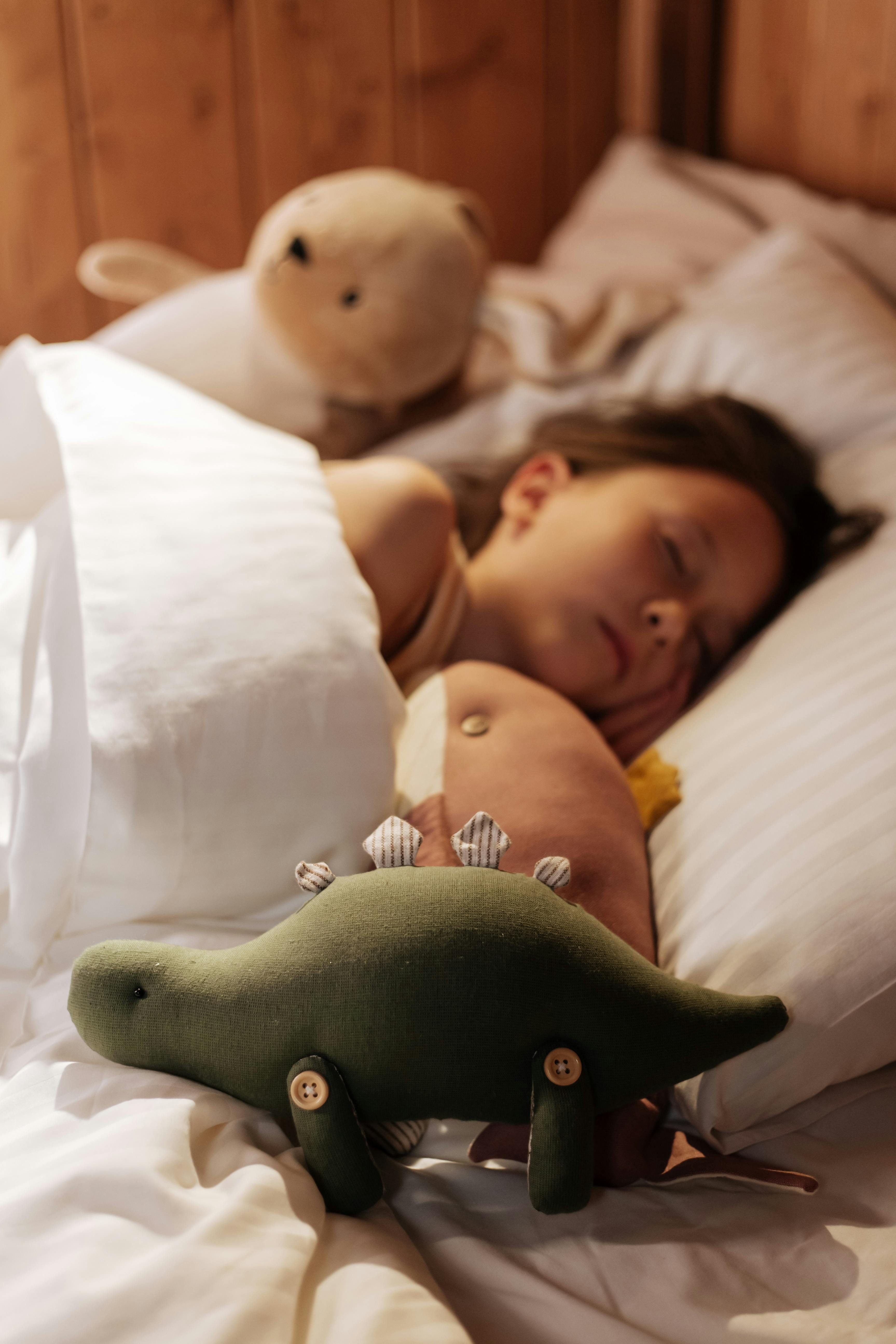 girl sleeping in bed surrounded by plush toys