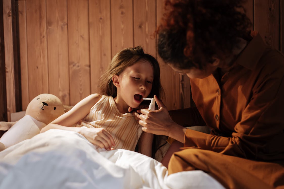 Free Mother Giving Her Daughter Medical Treatment for Flu Before Bedtime Stock Photo