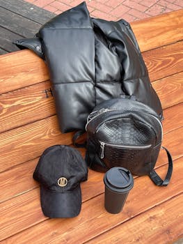 Collection of black fashion accessories on a wooden bench outdoors.