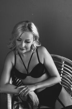 Intimate black-and-white portrait of a woman seated in lingerie, exuding elegance.