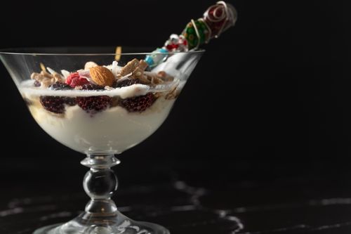 Free Close-up of a yogurt dessert with berries and nuts in a decorative glass on a dark background. Stock Photo