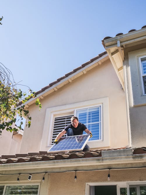 Free Man in Blue Shirt and Black Pants Sitting on Roof Stock Photo