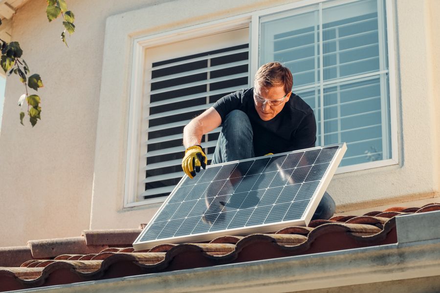 Solar technician installing a photovoltaic panel on a rooftop, promoting renewable energy.