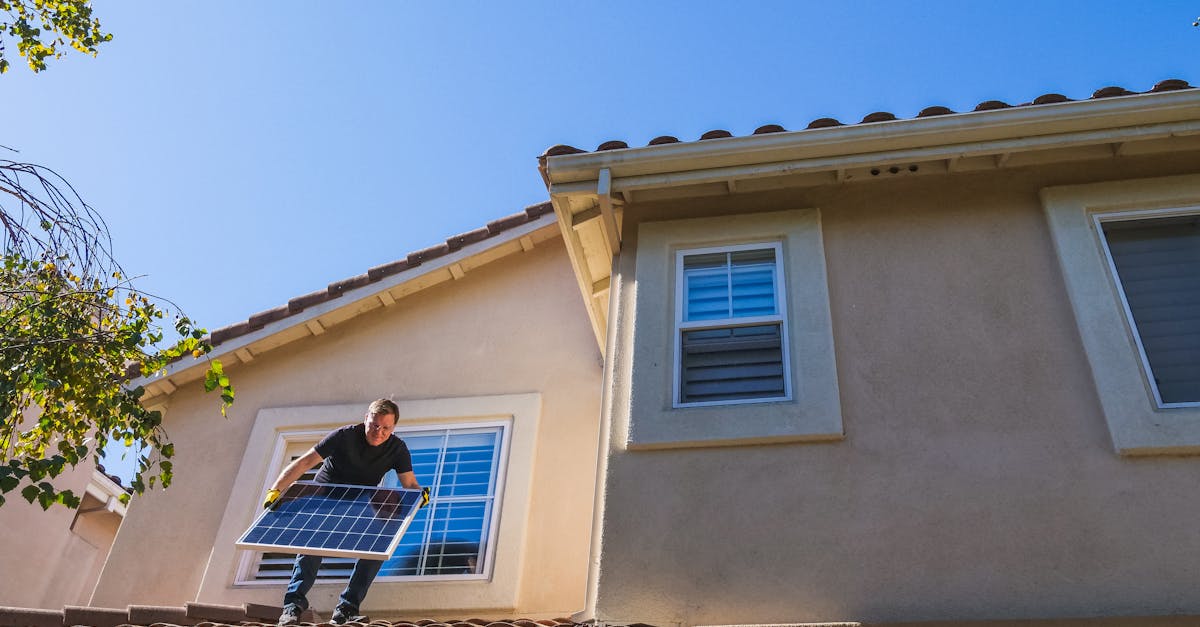Man installing a solar panel on a rooftop under a clear blue sky, promoting renewable energy.
