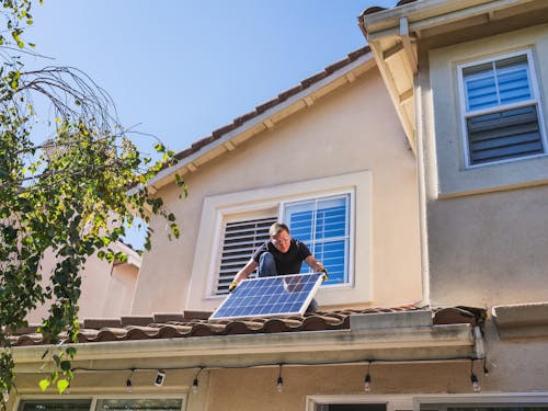 A Man Inspecting a Photovoltaic Panel on the Roof