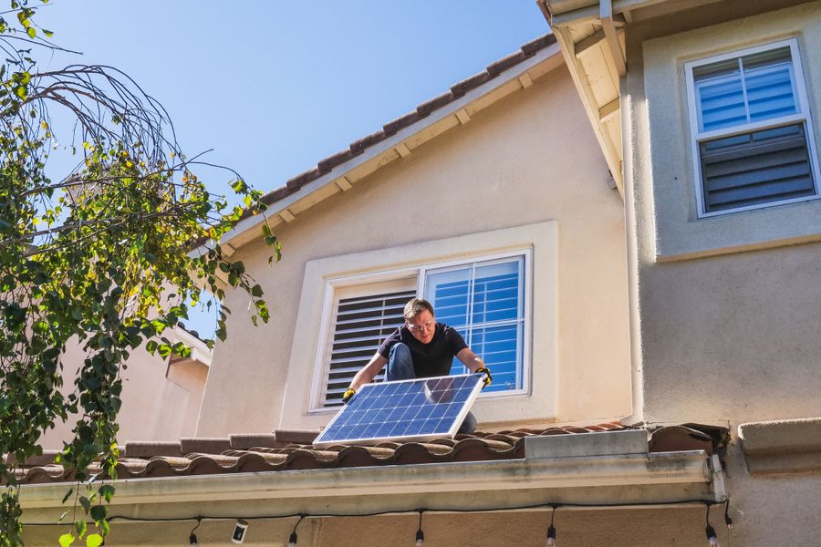 Solar technician installing photovoltaic panels on a sunny rooftop.