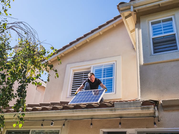 A Man Inspecting A Photovoltaic Panel On The Roof