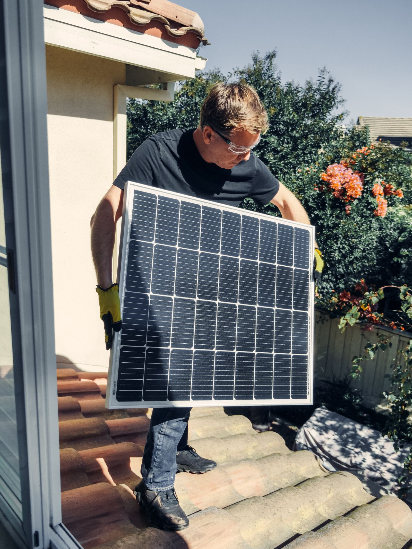 Installer positioning a solar panel on a roof