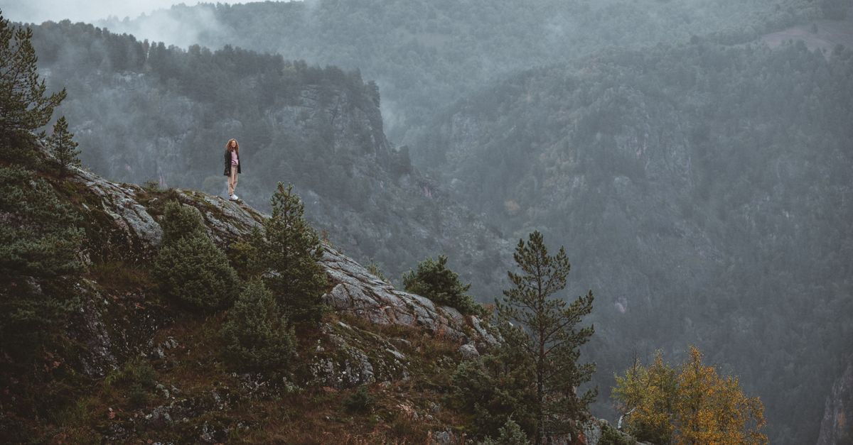 mountain landscape with fog and solitary figure praying in nature
