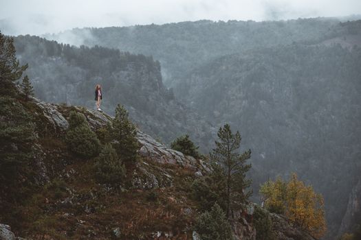 A lone figure stands amidst a misty mountainous landscape, evoking solitude and adventure.