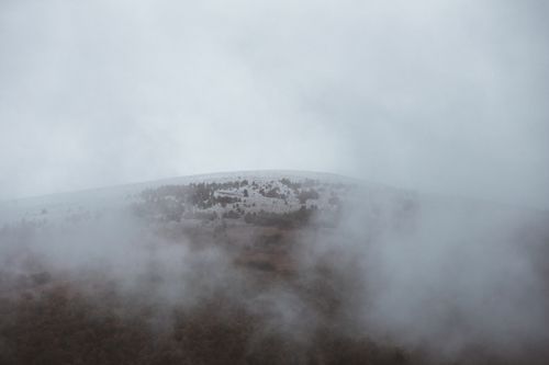 Free A scenic aerial view of a misty mountain landscape shrouded in fog and clouds. Stock Photo