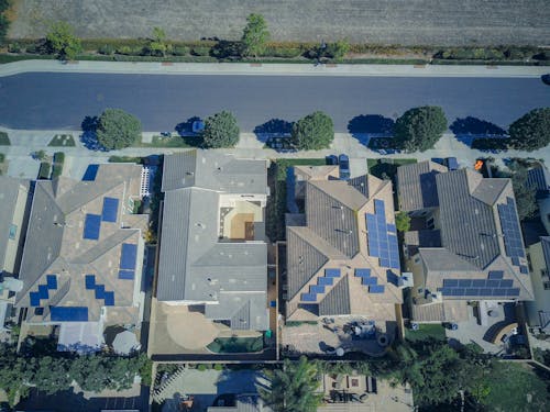 Aerial View of Houses with Solar Panels Along the Road