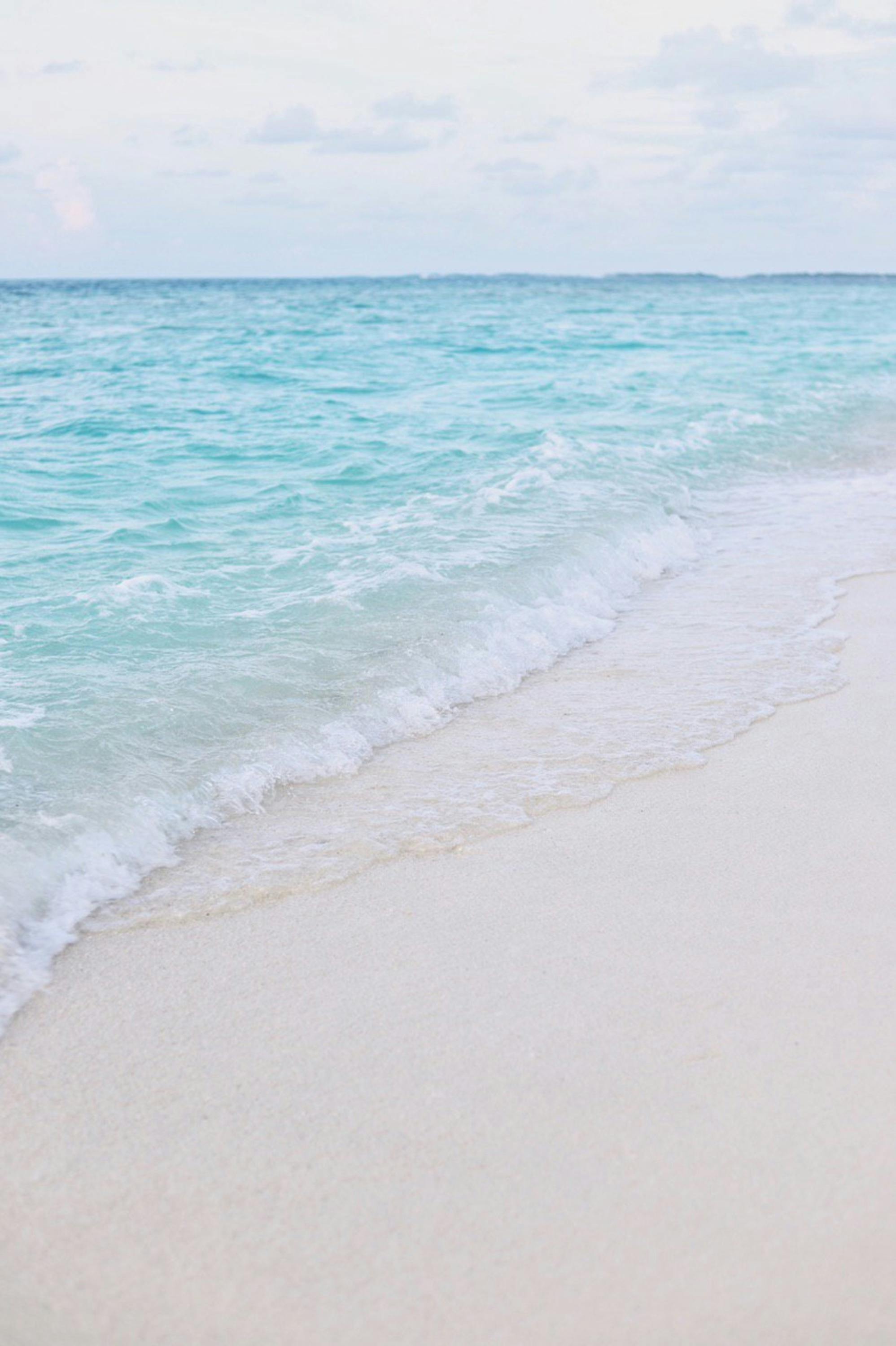 Relaxing view of turquoise waves gently lapping on a pristine Maldivian shoreline.