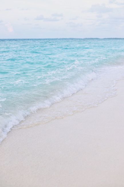 Relaxing view of turquoise waves gently lapping on a pristine Maldivian shoreline.