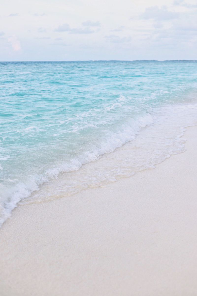 Turquoise waves gently reaching a pristine Maldivian shoreline.
