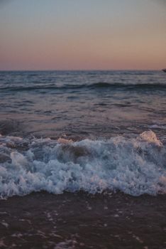 Tranquil waves softly break on a peaceful beach during a picturesque sunset.