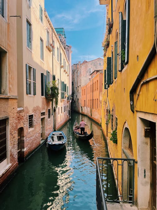 Free Person on a Gondola Traveling a Narrow Canal Stock Photo