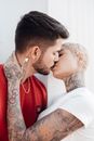 Heterosexual Couple Dressed in T-shirts with Tattoos Kissing with Love