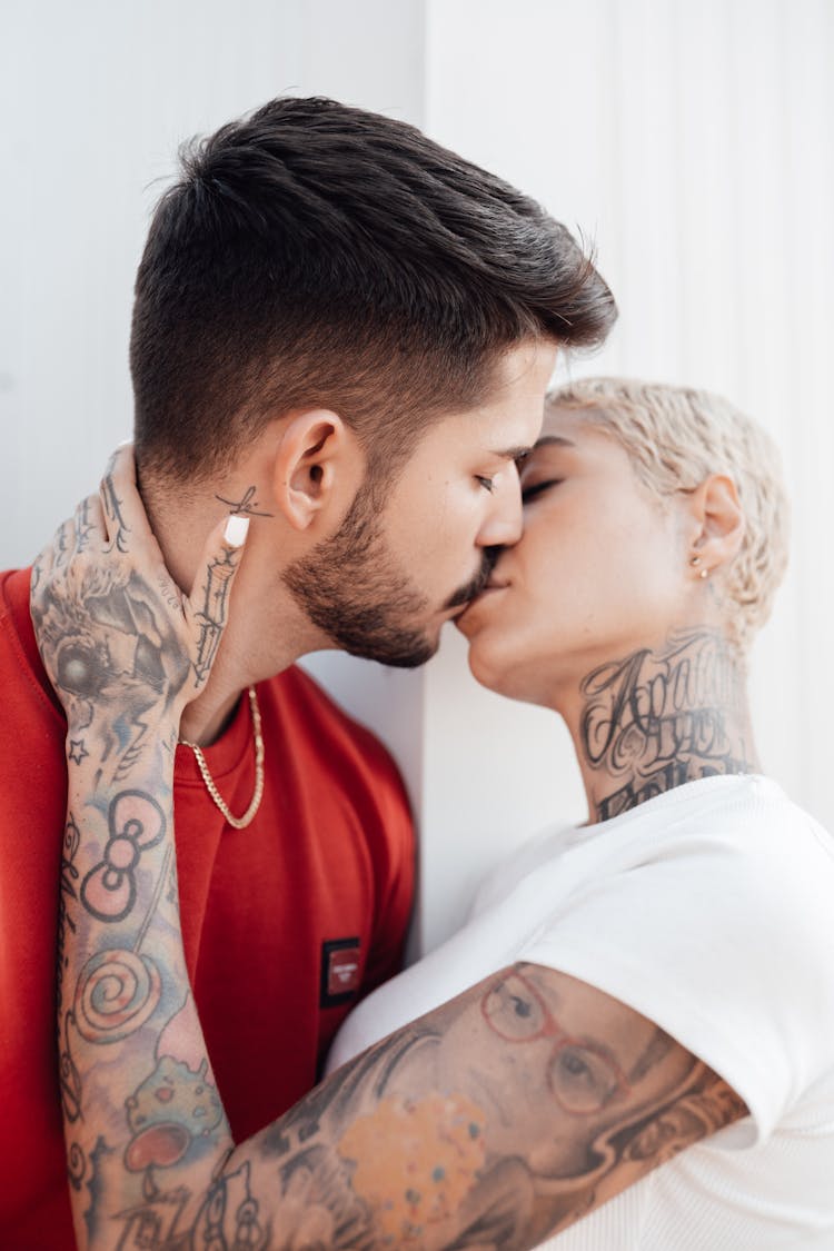 Heterosexual Couple Dressed In T-shirts With Tattoos Kissing With Love