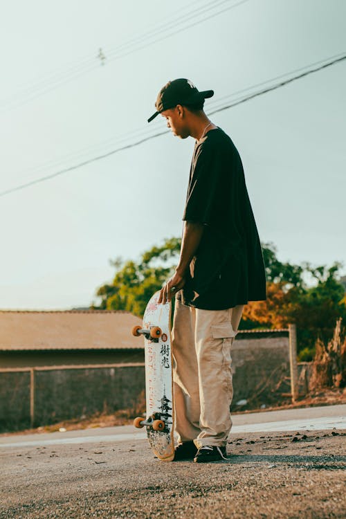 Man Standing and Holding Skateboard