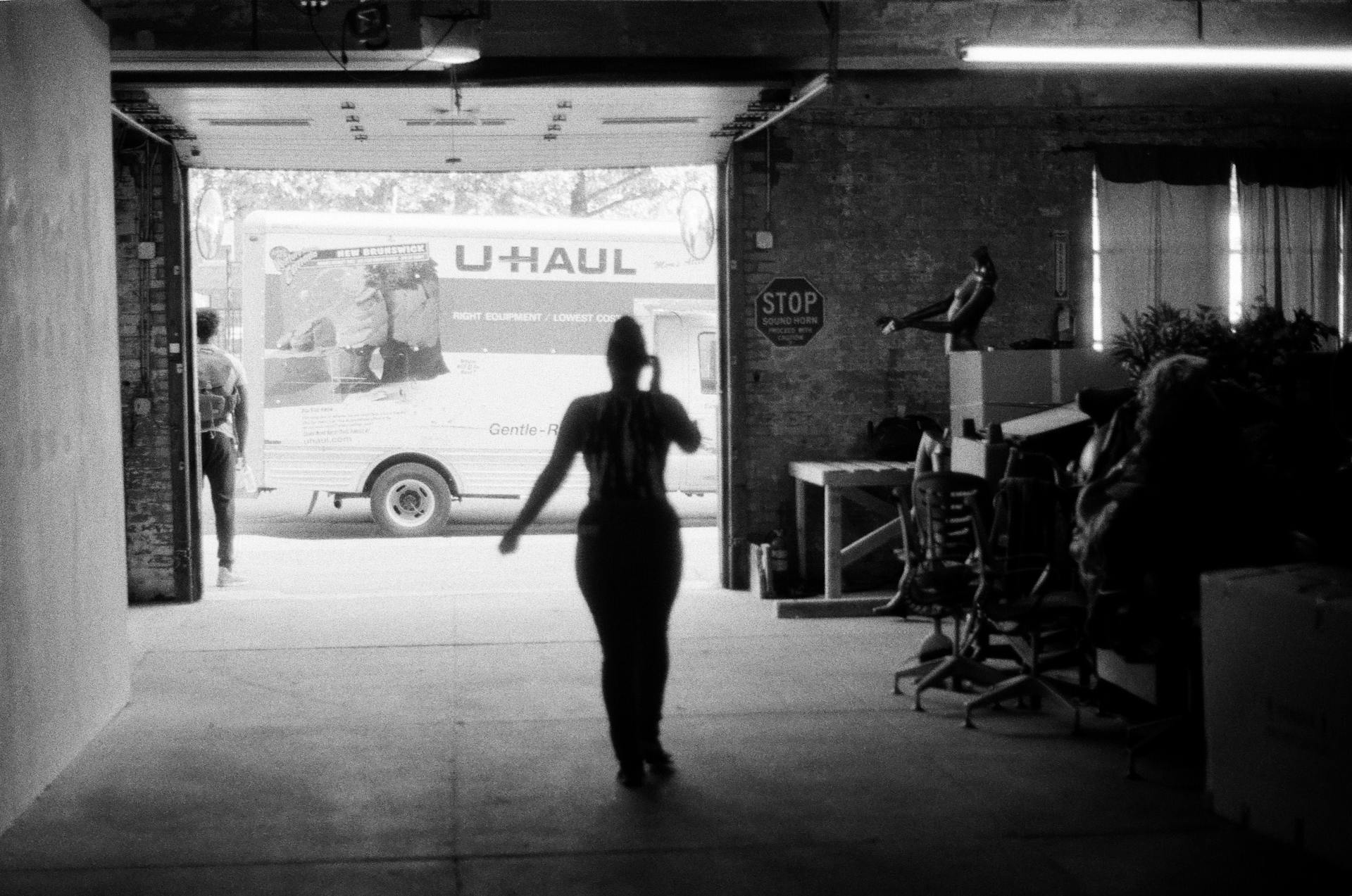 Silhouetted view of people and a U-Haul truck in a warehouse setting.