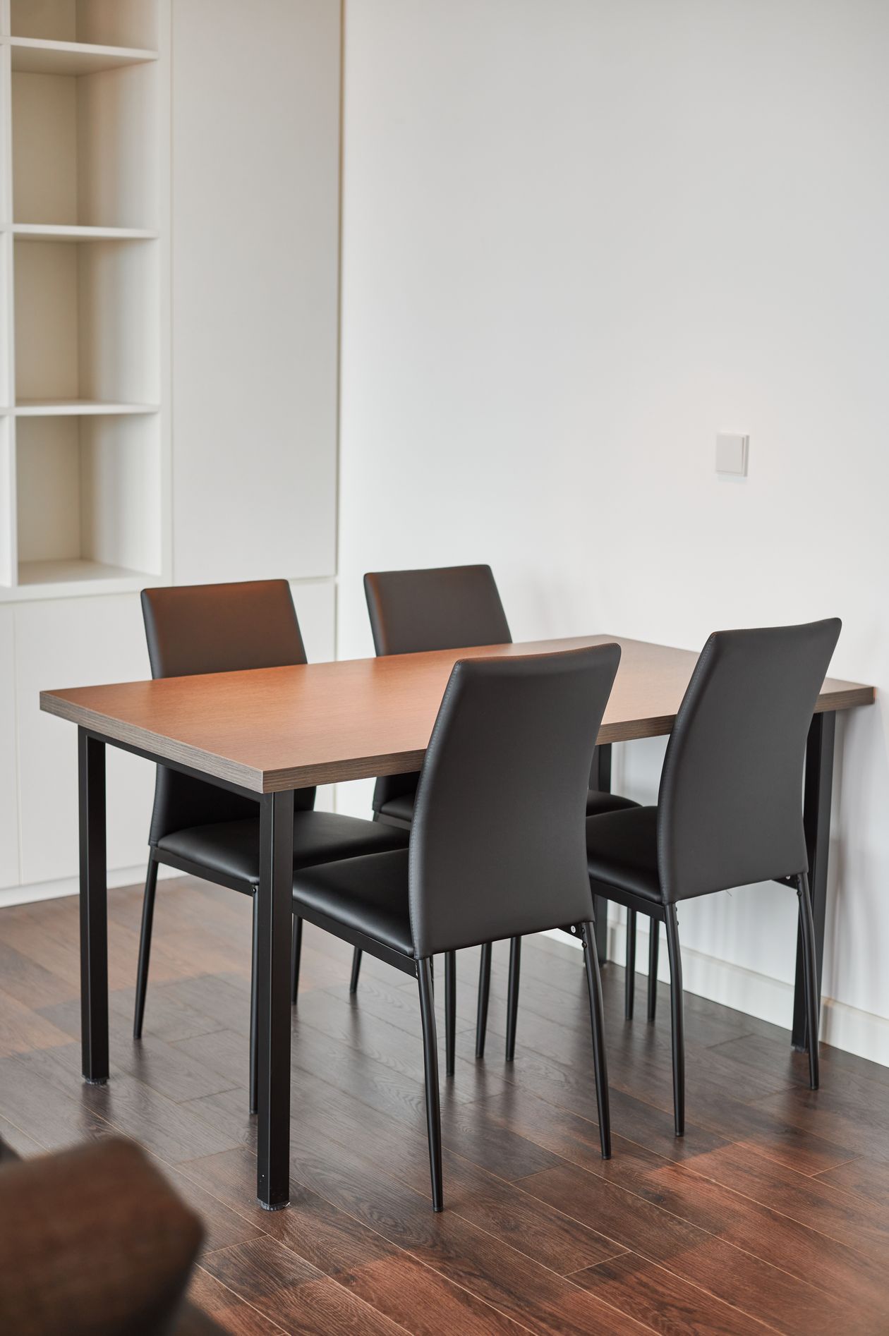 Rectangular wooden dining table with four black leather chairs