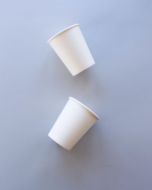 Free A minimalist flat lay of two white paper cups on a grey background. Stock Photo