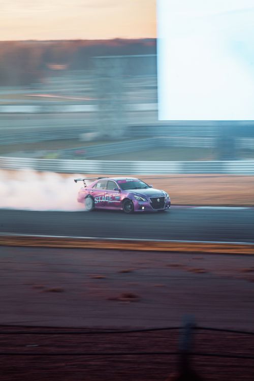 Free A race car drifting at high speed on a track, generating smoke with blurred motion effect. Stock Photo