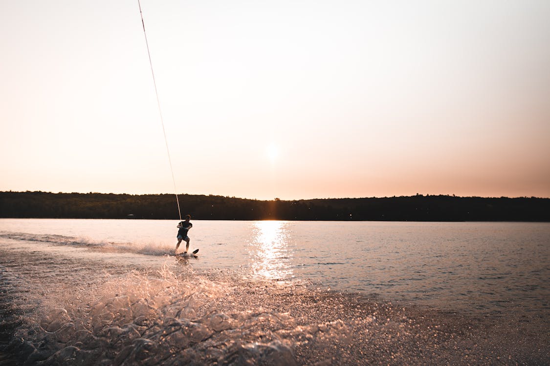 Free Male water skiing on calm lake under tenderly pink sky during summer vacation Stock Photo
