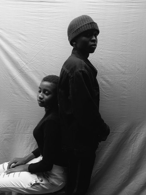 Free Black and white portrait of two individuals in a fashion pose against a simple backdrop. Stock Photo