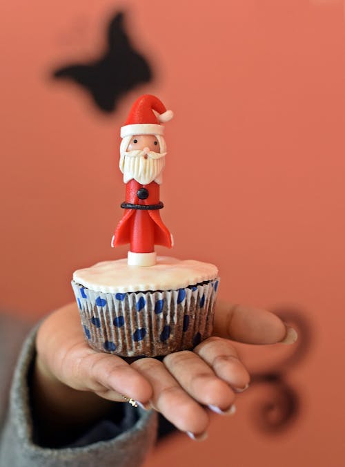 A Hand Holding a Cupcake with Santa Claud Toppings