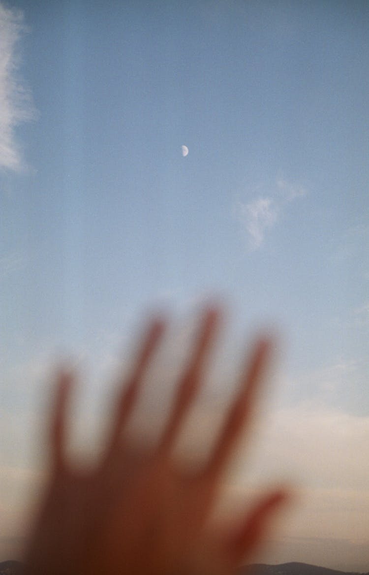 Moon On Sky During Day Seen Through Human Hand