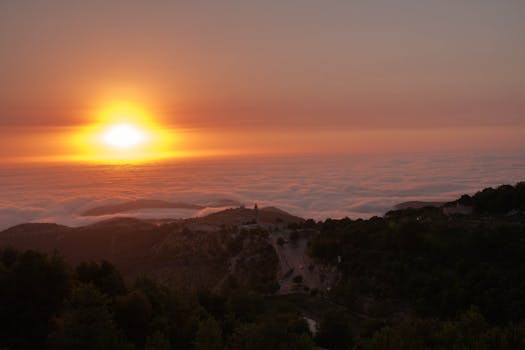 Stunning sunset over a misty mountain landscape with vibrant colors and clouds.