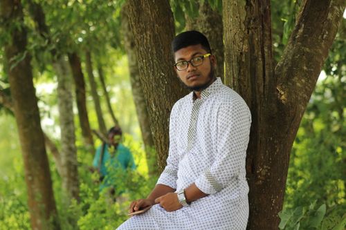 Free A young man in traditional attire enjoys a serene day outdoors in a lush park. Stock Photo