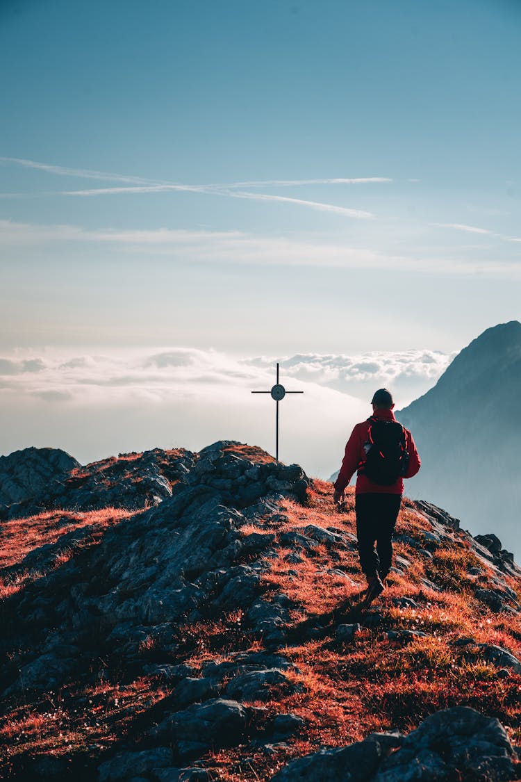 Man Walking Towards The Cross On The Top Of The Mountain