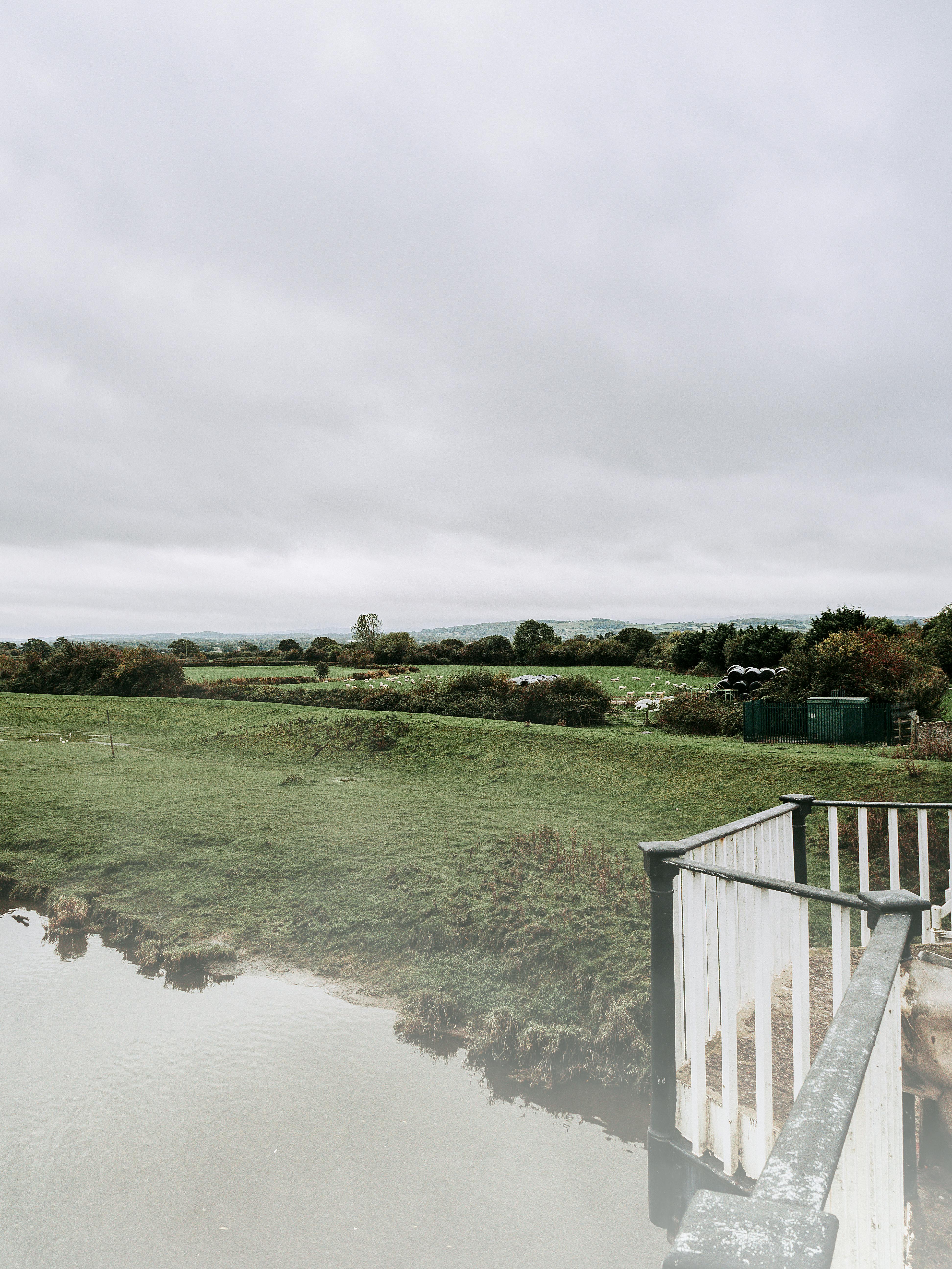A serene landscape of the Welsh countryside with lush fields and overcast skies, capturing rural tranquility.