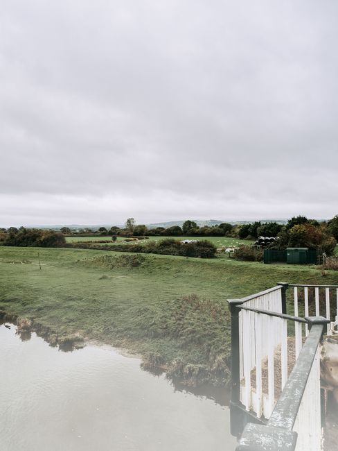 A serene landscape of the Welsh countryside with lush fields and overcast skies, capturing rural tranquility.