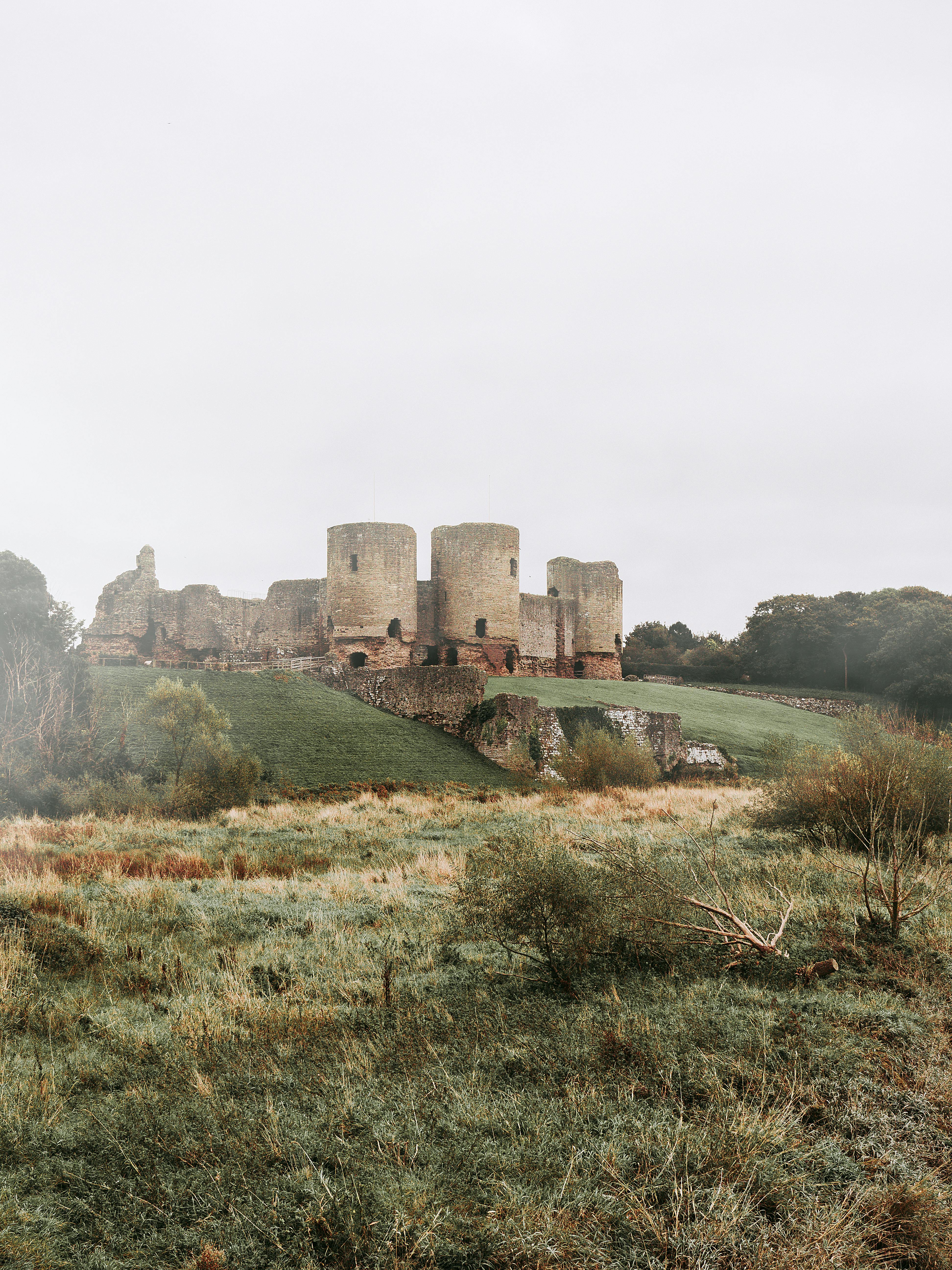 Capture of Rhuddlan Castle ruins amidst lush greenery in Wales, UK.
