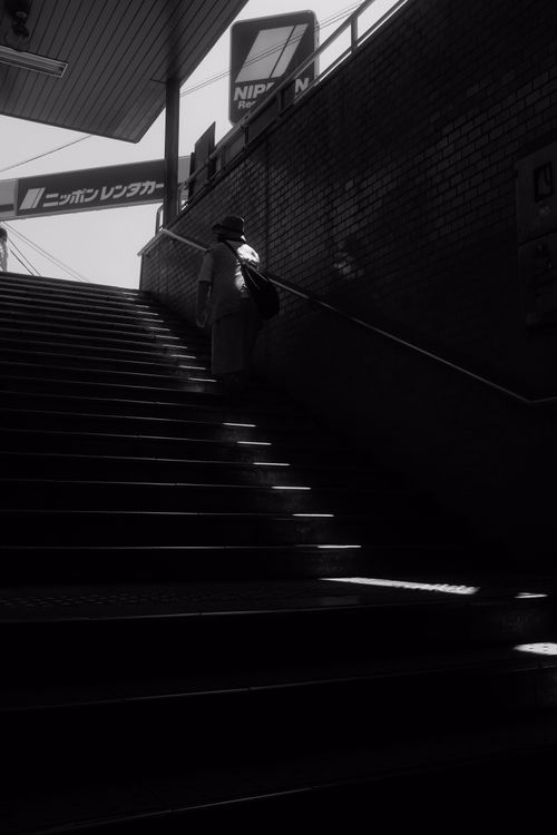 Free Black and white photo of a person on urban stairs with dramatic shadows. Stock Photo