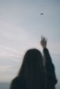 Woman Reaching Towards Airplane in Sky