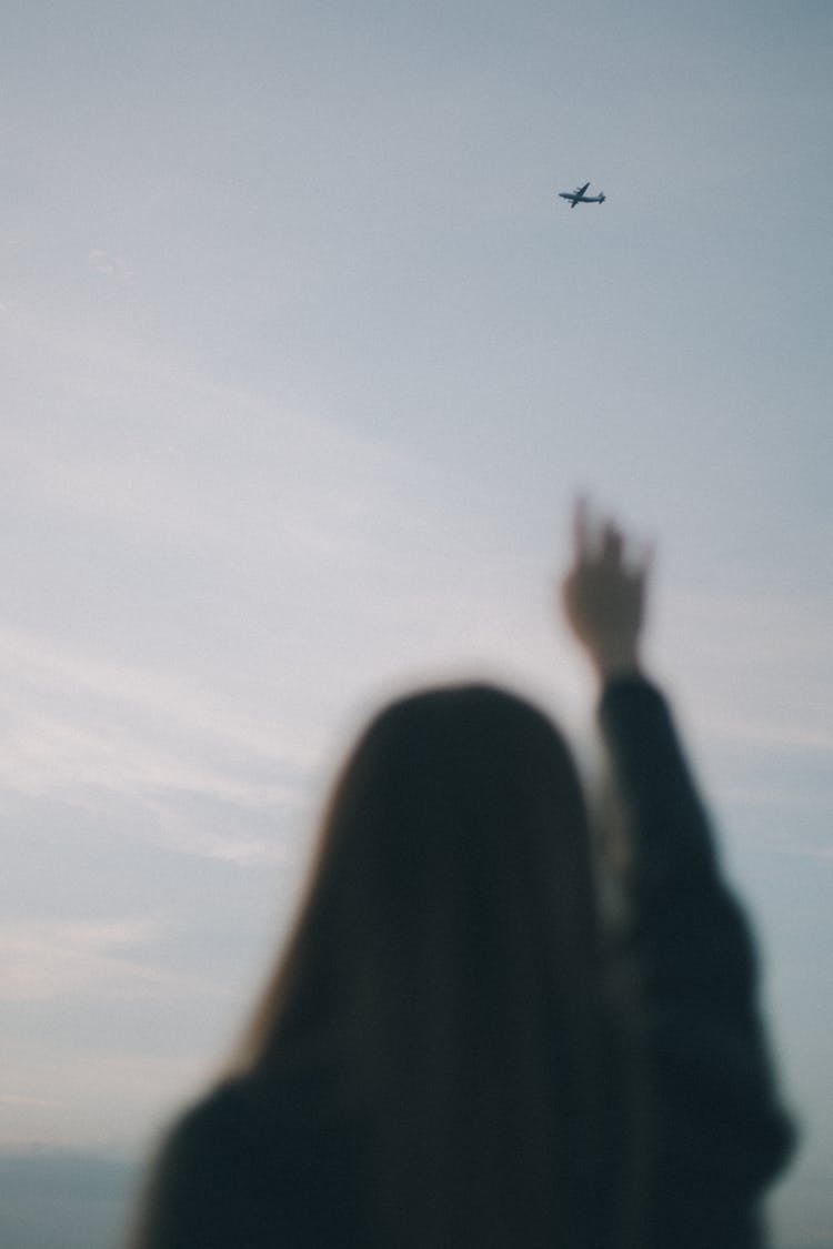 Woman Reaching Towards Airplane In Sky