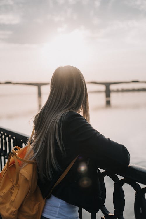 Woman With Backpack on Bridge at Sunset