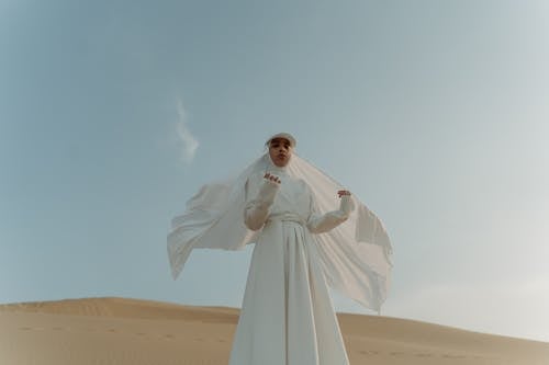 A Woman Wearing a White Outfit and a Hijab in the Desert