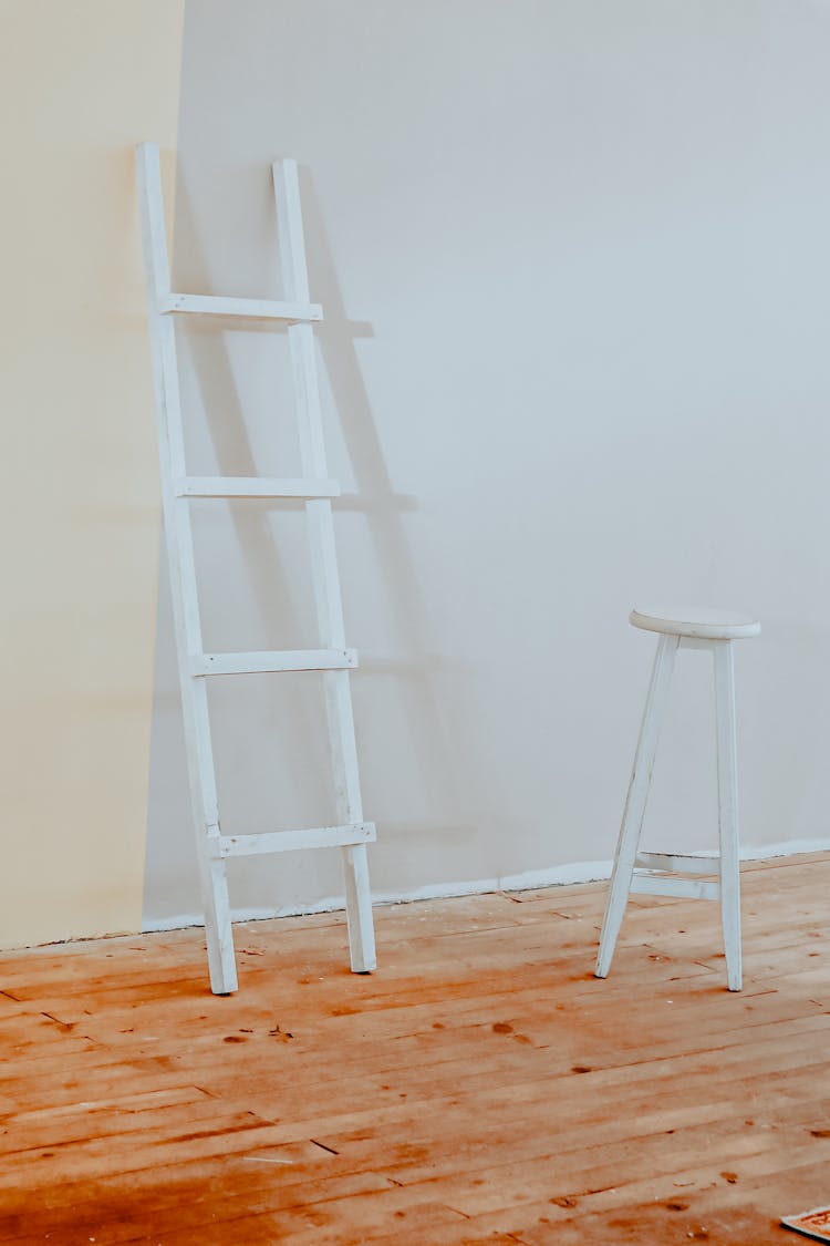 A White Wooden Ladder Leaning On The Wall