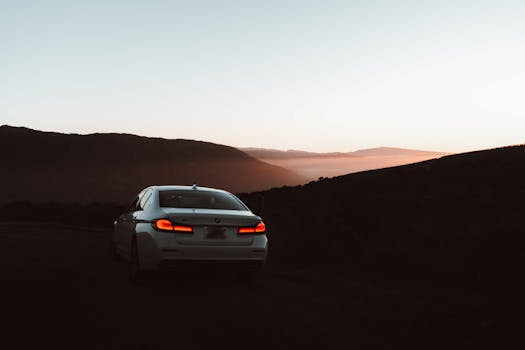 A BMW car parked at sunset in a scenic mountain area, creating a serene and luxurious atmosphere.