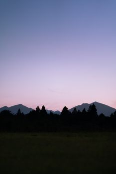 Peaceful twilight view of silhouetted mountains and trees in Japan, capturing the serene evening sky.