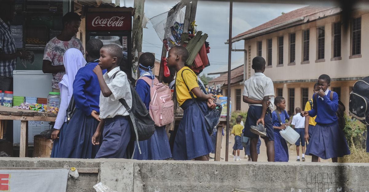 Group of students in uniforms near a market stall outside school.