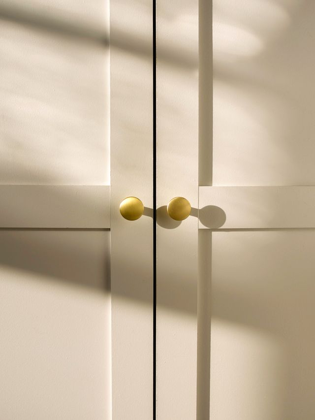Two brushed brass knobs on cream cupboard doors — Kulbir on Pexels